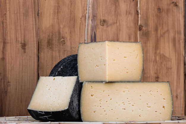 Tête ronde de fromage à pâte dure avec une petite tranche coupée sur bois