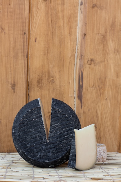 Tête ronde de parmesan à pâte dure avec une petite tranche coupée sur bois