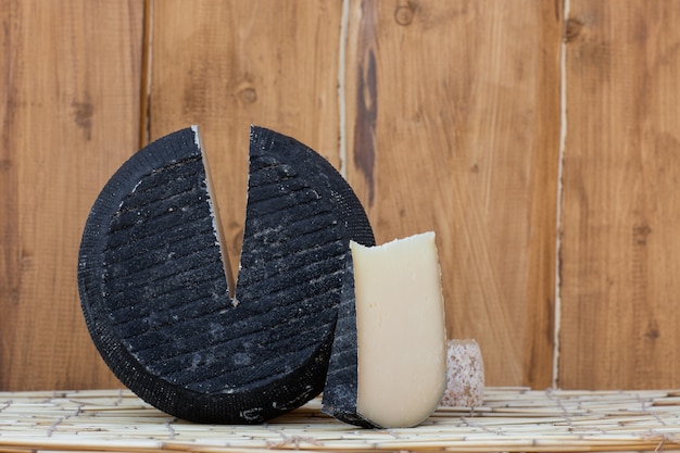 Tête ronde de parmesan à pâte dure avec une petite tranche coupée sur bois