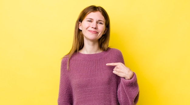 Tête rouge jolie femme à la fière confiante et heureuse souriante et pointant vers soi ou faisant le signe numéro un