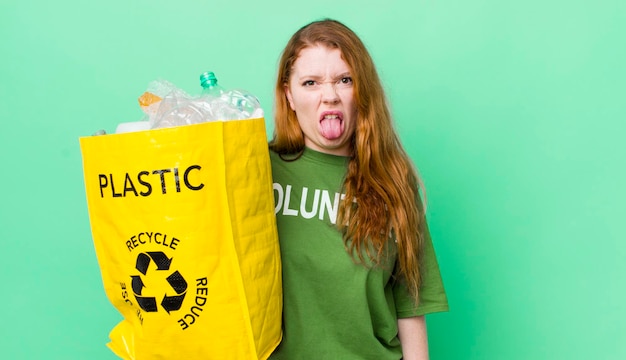 Tête rouge jolie femme se sentant dégoûtée et irritée et langue dehors concept de recyclage