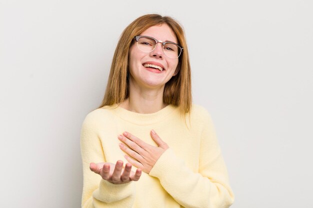 Photo tête rouge jolie femme se sentant heureuse et amoureuse souriante avec une main à côté du cœur et l'autre tendue à l'avant