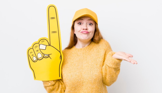 Tête rouge jolie femme se sentant perplexe et confuse et doutant du concept de ventilateur à main numéro un