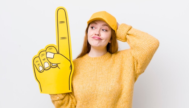 Tête rouge jolie femme souriant joyeusement et rêvassant ou doutant du concept de ventilateur à main numéro un