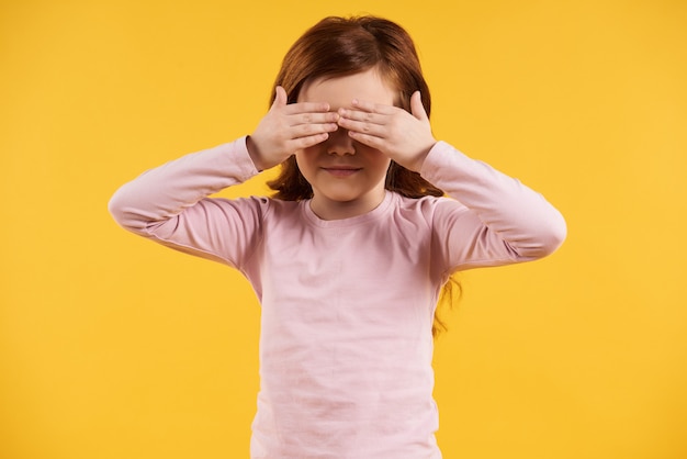 Tête rouge petite fille ferme les yeux avec les mains