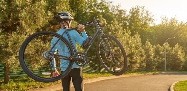 En-tête de site Web d'un homme athlétique fort en tenue de sport tenant un vélo en se tenant debout dans un parc