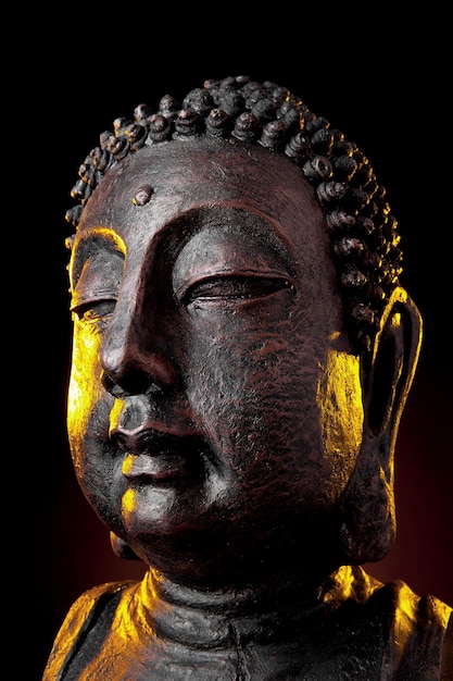 Tête de statue de bouddha close-up avec lueur sur fond noir