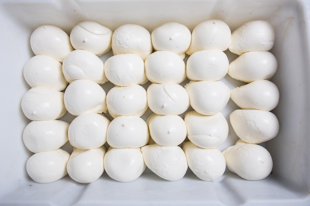 Têtes de fromage mozzarella fraîches allongées dans des boîtes sur une production