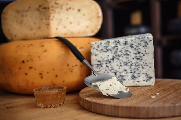 Têtes de fromage avec des tranches et des couteaux sur une planche de bois avec un intérieur