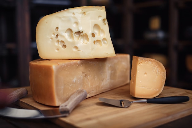 Têtes de fromage avec des tranches et des couteaux sur une planche de bois avec un intérieur