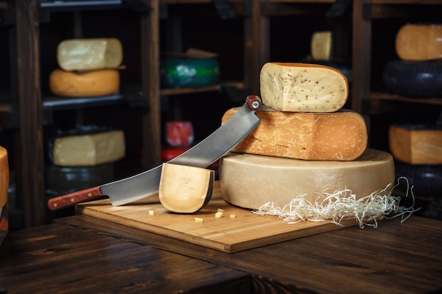 Têtes de fromage avec des tranches et des couteaux sur une planche de bois avec un intérieur