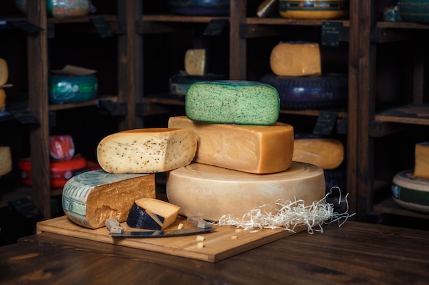 Têtes de fromage avec des tranches et des couteaux sur une planche de bois avec un intérieur