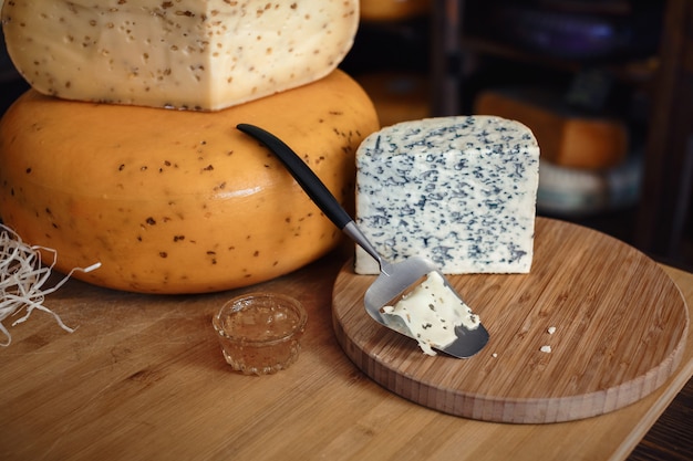 Photo têtes de fromage avec des tranches et des couteaux sur une planche de bois avec un intérieur