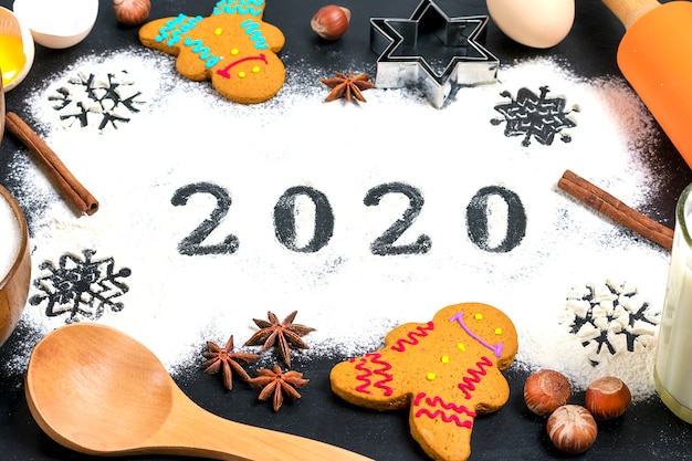 Texte 2020 fait avec de la farine avec des décorations sur fond noir.