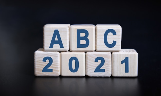 Texte ABC 2021 sur des cubes en bois sur fond noir avec reflet.