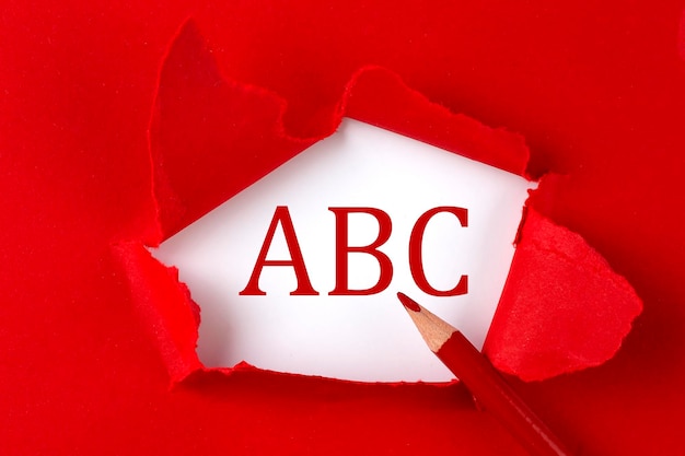 Texte d'ABC sur le papier déchiré rouge avec le crayon rouge