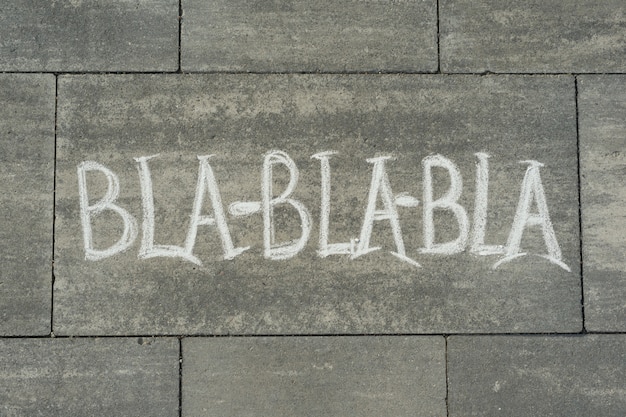 Texte bla-bla-bla écrit sur le trottoir gris