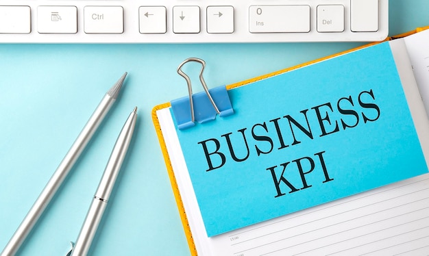 Texte BUSINESS KPI sur autocollant sur fond bleu avec stylo et clavier