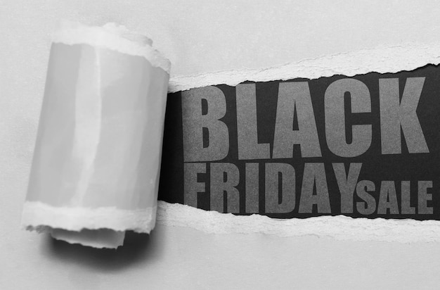 Photo texte de concept de vente vendredi noir sur trou de papier déchiré de vue rapprochée gris