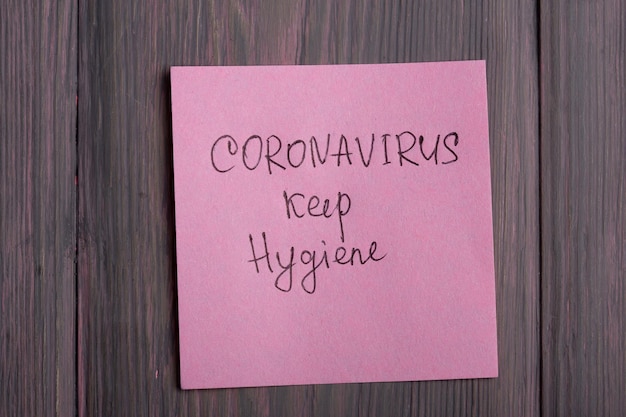 Texte Coronavirus garder l'hygiène sur une note collante sur fond de bois