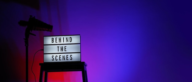 Texte des coulisses sur Lightbox ou Cinema Light box. Boîte à lumière du film sur l'escalier du studio et trépied léger Snoot sur fond dégradé de couleurs. L'équipe Représenter dans les coulisses travaille sur.