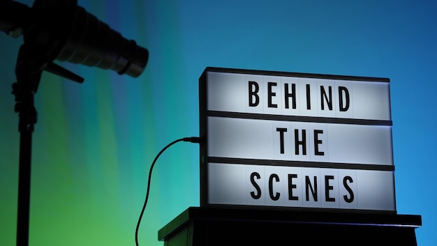 Texte des coulisses sur Lightbox ou Cinema Light box. Boîte à lumière du film sur l'escalier du studio et trépied léger Snoot sur fond dégradé de couleurs. L'équipe Représenter dans les coulisses travaille sur.