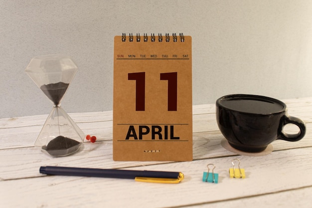 Photo texte de date du calendrier du 11 avril sur bloc de bois blanc avec papeterie sur bureau en bois