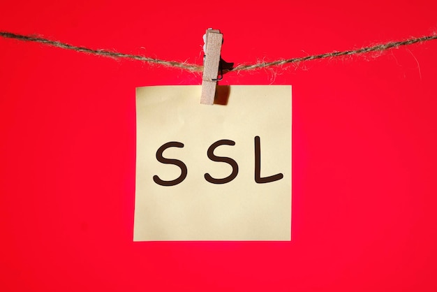 Texte Du Concept Ssl Secure Sockets Layer Sur Un Autocollant Jaune Sur Une Pince à Linge Avec Une Corde Sur Fond Rouge