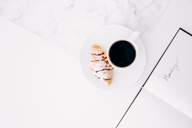 Photo texte du lundi sur le journal avec tasse à café et croissant sur le bureau blanc