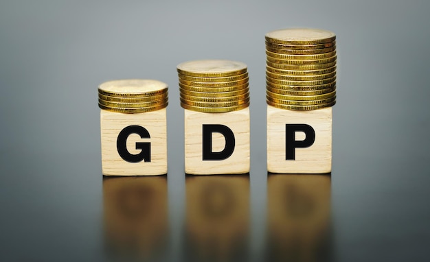 Texte du PIB sur un bloc de bois avec des pièces de monnaie sur le dessus, concept commercial et financier.
