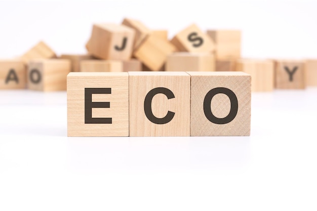 Le texte ECO Economic Cooperation Organization est écrit sur trois cubes en bois debout sur une table blanche en arrière-plan une montagne de cubes en bois avec des lettres