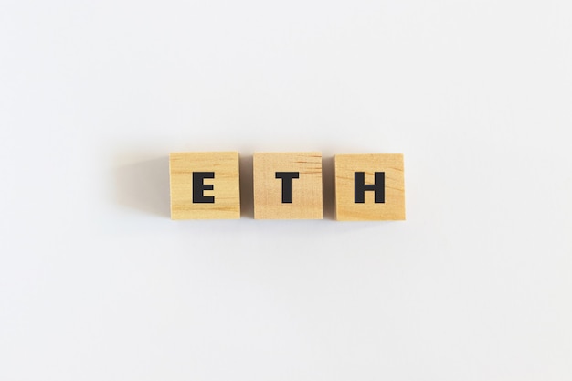Texte ETH (Ethereum) sur des cubes en bois sur fond BLANC. Ondulation. Monnaie crypto. Acheter et vendre. Vue de dessus, mise à plat.