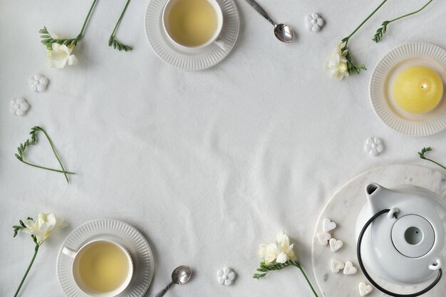 Texte Joyeuses Fêtes sur le tableau des lettres avec des fleurs de freesia printanières et une tasse de thé sur la table