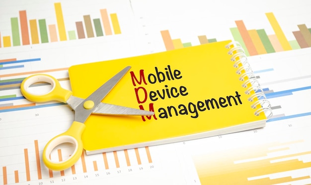 Texte MDM en tant que MOBILE DEVICE MANAGEMENT sur un ordinateur portable et une calculatrice jaunes