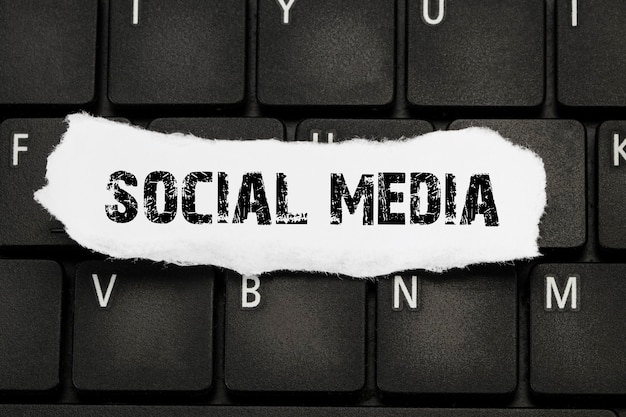 Texte des médias sociaux sur du papier déchiré sur le clavier.