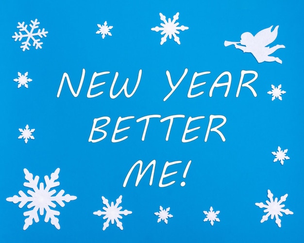 Photo texte nouvel an mieux moi sur fond bleu avec des flocons de neige de noël un ange blanc changements en vous-même