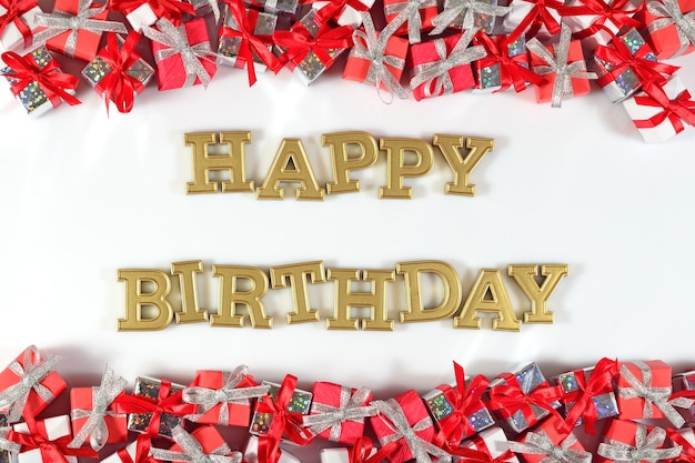 Photo texte d'or de joyeux anniversaire et cadeaux argentés et rouges sur un fond blanc