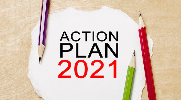 Texte PLAN D'ACTION 2021 sur un bloc-notes blanc avec des crayons sur un fond en bois. Concept d'entreprise