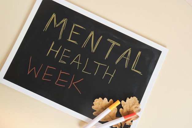 Texte semaine de la santé mentale sur tableau noir et feuilles de chêne d'automne aidant les personnes ayant des problèmes mentaux