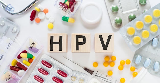 Texte VPH écrit avec des cubes en bois Stéthoscope et fond de pilules sur bois avec des mots du virus du papillome humain VPH comme concept médical
