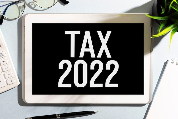 Textez TAXE 2022 sur tablette, calculatrice, lunettes, bloc-notes. Notion de comptabilité. Mise à plat.