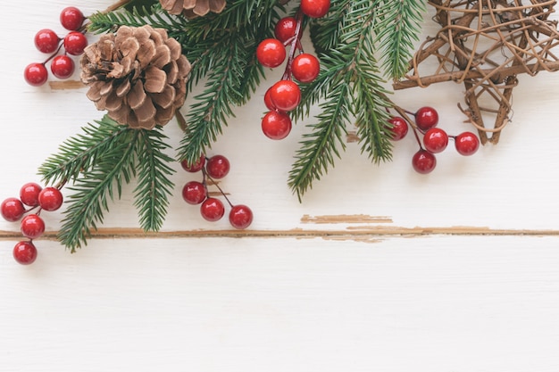 Photo texture bois blanc avec feuille de pin, pommes de pin ou cône de conifère, boules de houx rouges et étoile en bois dans le concept de noël. fond de planche de bois en vue de dessus à plat avec espace de copie pour le papier peint de noël.