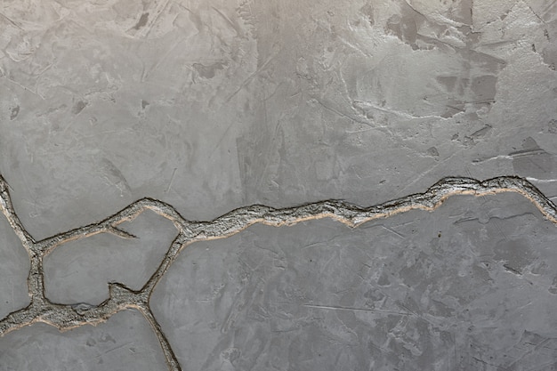 La texture du mur de béton gris est ornée d&#39;une profonde fissure de couleur argentée.