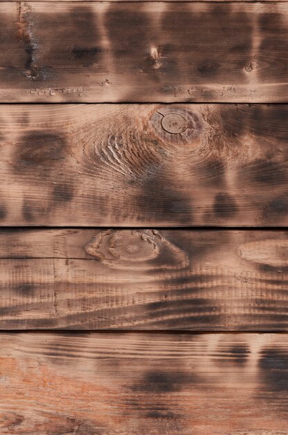 La texture du mur en bois brûlé. Mur de longues planches en bois orange lisse avec une texture de friture noire spécifique