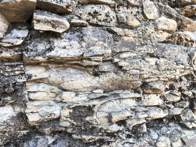 La texture du mur de pierre de bouffée grise naturelle rugueuse convexe fissurée de vieilles briques de pierre anciennes dans la roche L'arrière-plan