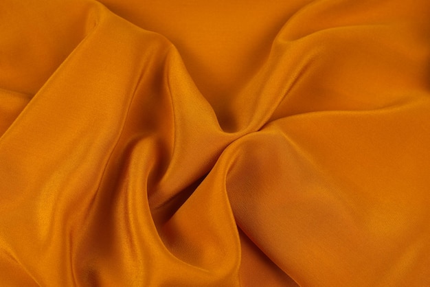 La texture du tissu de luxe en soie dorée ou en satin peut être utilisée comme arrière-plan abstrait. Vue de dessus.