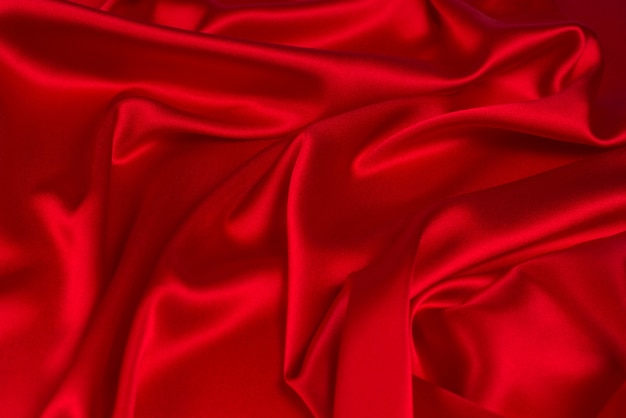 La texture du tissu de luxe en soie rouge ou en satin peut être utilisée comme arrière-plan abstrait. Vue de dessus.