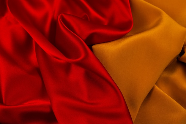 La texture du tissu de luxe en soie ou en satin rouge et orange peut servir de fond abstrait.