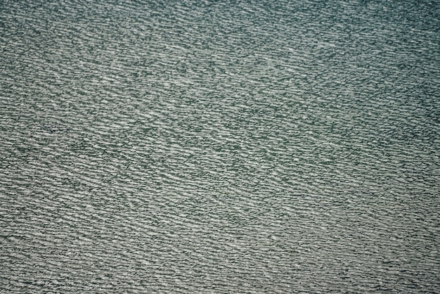 Texture d'eau calme vert foncé du lac. Ondulations méditatives à la surface de l'eau. Nature fond minimal de lac vert profond. Toile de fond naturelle d'eau turquoise foncée claire. Plein cadre de fragment de lac