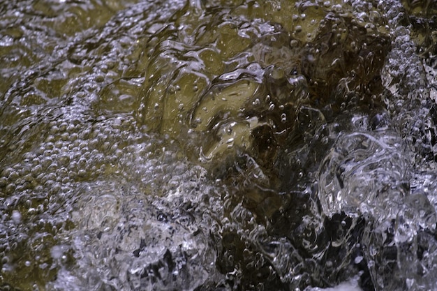 Texture de l'eau à l'état naturel dans une rivière lors des éclaboussures contre les pierres